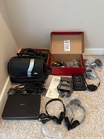 Overview of all items in the lot including bag, portable DVD/CD player, Walkmans, headphones, cords, manuals, and box.