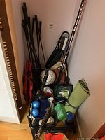 Wide angle showing all sports items packed in corner including golf clubs, tennis rackets, soccer ball, bocce balls, baseball glove, yoga mat, and sport rack.