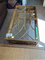 Top view of the rattan coffee table with glass top showing decorative rattan weaving and brass/gold fasteners.