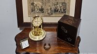 Lot overview with Kundo anniversary clock, Bulova compact clock, iron bracelet, and jewelry box.