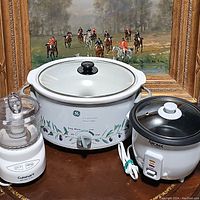 Photo showing all three appliances: Cuisinart chopper, GE slow cooker, Aroma rice cooker in front of a framed painting.