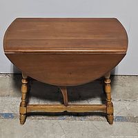 Photo of the drop leaf side table with leaves down, showing rounded shape and wood grain top