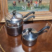 Two stainless steel saucepans, one 2.5 qt with lid and two handles and one 1 qt with lid and one handle.