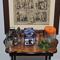 Photo of all kitchen tools including metal sifter, grater, travel beverage maker, measuring cup, juicer, and plastic canisters with orange lids