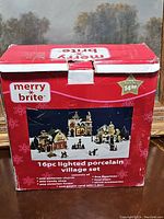 Box displaying set name, contents, and price sticker showing $14.99, indicating 16 pieces including buildings, figures, trees, accessories, and power cord.