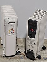Photo of two white oil-filled radiator space heaters, one Lakewood and one DeLonghi, standing side by side on floor.