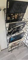 Close-up photo showing one of the metal wall hanging record racks holding vinyl record covers.