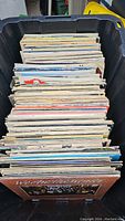 Top-down view of large mixed lot of vinyl records in a plastic bin