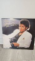 Front cover of Michael Jackson Thriller vinyl album showing Michael Jackson reclining in a white suit jacket and black shirt.