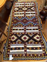 Full-length view of carpet laid on hardwood floor showing entire pattern and border.