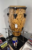 Large bongo drum on tripod stand with small patriotic drum in front and vinyl records at edges