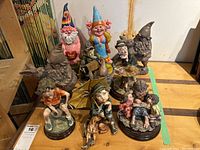 Overview photo showing all nine figurines arranged in rows on a wooden table, including gnomes, a musician, children, and other characters.