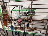 Full view of cultural wall display items showing dreamcatcher and two hanging orbs with tassels against a slat wall.