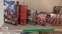 Photo showing multiple boxed games including Warhammer 40,000 Mont'ka and others on a shelf