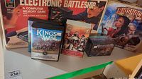 Photo showing Electronic Battleship, Kings of War disc, Butcher's Guild character set, Nightfall Blood Countess card game, and Bioshock Infinite box.