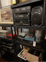 Full view of shelving loaded with stereo components, speaker, painting and accessories