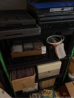 Pioneer LaserDisc player and shelving holding assorted boxes and media items.