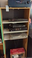 Photo shows wooden shelving unit with multiple stereo components including a turntable with dust cover, Sony and RCA devices, and other audio equipment stacked.