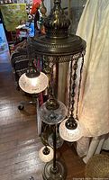 Front view of full Turkish-style floor lamp showing five hanging crackle glass shades and ornate top