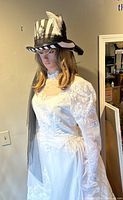 Front view of mannequin wearing dress, hat, veil and glasses