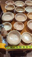 Photo showing collection of various wood carved bowls with natural wood grains arranged on a table.