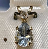 Close-up photo of the pear-shaped aquamarine pendant with a small round gemstone in 10K gold setting.