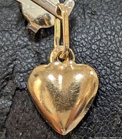 Close-up front view of a heart-shaped yellow gold pendant with a rectangular bail.