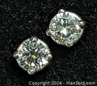 Close-up view of one diamond stud in 14KT gold four-prong setting against black background