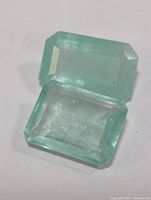 Two rectangular faint green emerald cut stones side-by-side on white background