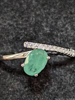 Top view showing oval emerald and cubic zirconia accents on sterling silver band.