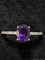 Close-up photo of sterling silver ring with oval purple amethyst stone on black background.