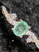 Close-up photo of the sterling silver ring showing the oval emerald gemstone and the cubic zirconia accented band.