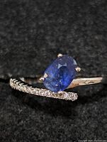 Close-up front view of the sterling silver ring highlighting the deep blue oval sapphire and diamond accent stones along the curved band.