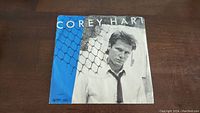 Front cover of the Corey Hart 'Sunglasses At Night' 45rpm vinyl single, featuring Corey Hart in a black and white photo and blue accent strip.