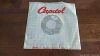 View of 'Come Together' vinyl single in original Capitol Records paper sleeve with gray grid pattern and red Capitol logo.