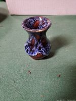 Small clay pottery bottle with bulbous shape and blue-purple mottled glaze.