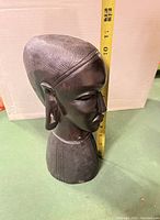 Side view of the dark ebony wood head bust with measuring tape showing approximately 13 inches height, illustrating detailed carving on the ear, face, and textured headtop.