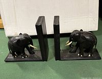 Side view of the pair of ebony elephant bookends with one showing a missing tusk.