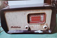 Front view of Electrohome AM radio showing brown casing, front speaker grill, two knobs, and dial window.