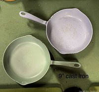 Top view of two enameled cast iron skillets, one blue and one green, showing the cooking surfaces and handles.