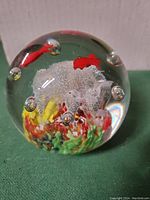 Single clear spherical glass paperweight with multicolor ocean-themed design inside, including air bubbles and coral-like formations.