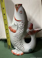 Photo of the koi fish ceramic pitcher showing orange and gold details, about 9 inches tall with measuring tape next to it.