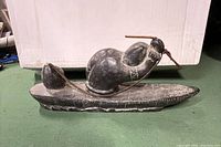 Full side view of the soap stone carving showing hunter in kayak holding spear.