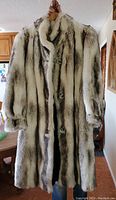 Front view of the vintage Tissavel faux fur coat hanging, showing the silver fox pattern and button closure.