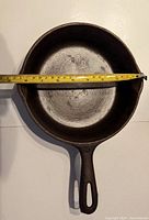 Top view of skillet showing 8.5 inch diameter measurement with measuring tape across the pan's inner width