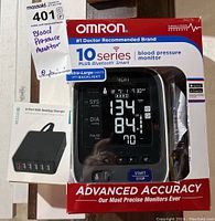 Omron 10 Series blood pressure monitor in original packaging showing front view with digital display and key features.