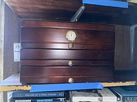 Front view of dark wood cigar humidor with analog hygrometer and multiple drawers