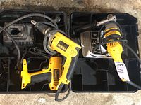 Top view showing both Dewalt power tools inside open carrying cases with power cords and side handle for grinder visible.