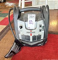 Full front view of the jump start battery showing cables wrapped around the sides, handle top center, and label with lot number and handwritten "jump start battery".