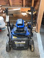 Front view of blue Kobalt 40V Max brushless electric mower with folded handle and charger placed on top